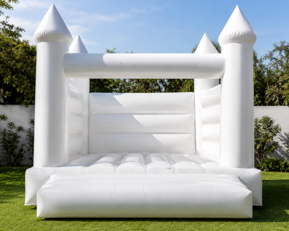 All-white inflatable bounce castle with four turrets set up on a green lawn